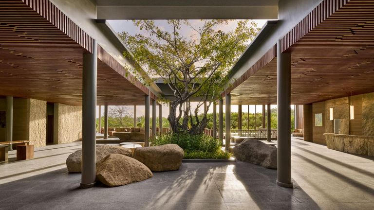 The arrival lobby – seemingly carved out of natural rock – creates a dramatic first impression, opening to serene views that overlook the resort’s expansive landscape.