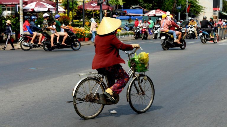 A woman rides her bicycle through a street market. | Source: Pexels.