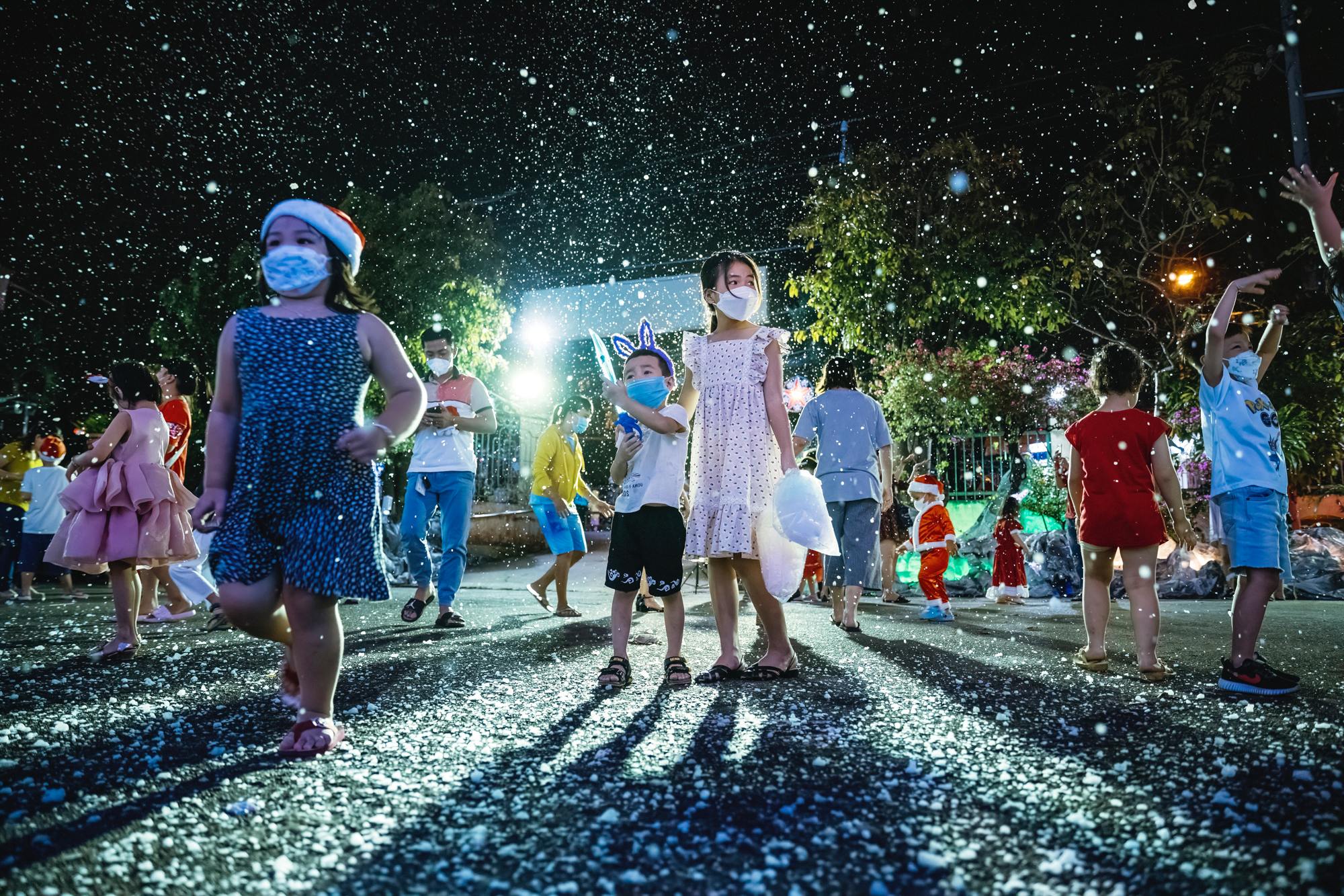 Children enjoy some snow soap bubbles at Bình An Thượng Church a night before Christmas Due to the pandemic everyone is still mandated to wear face masks when in public